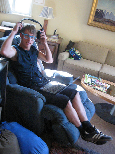 Man with headphones and laptop in easy chair